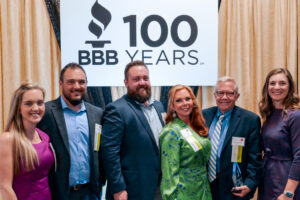 Greentree owners dressed in formal attire pose with the Legacy Award at a "BBB 100 Years" event.